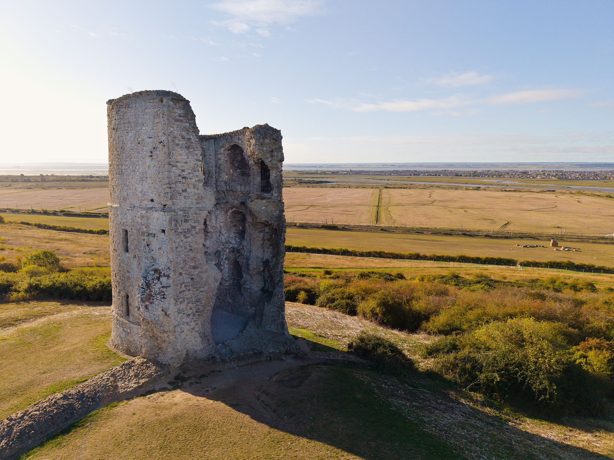 Aerial photograph of a historic stone tower standing above open countryside during warm evening light