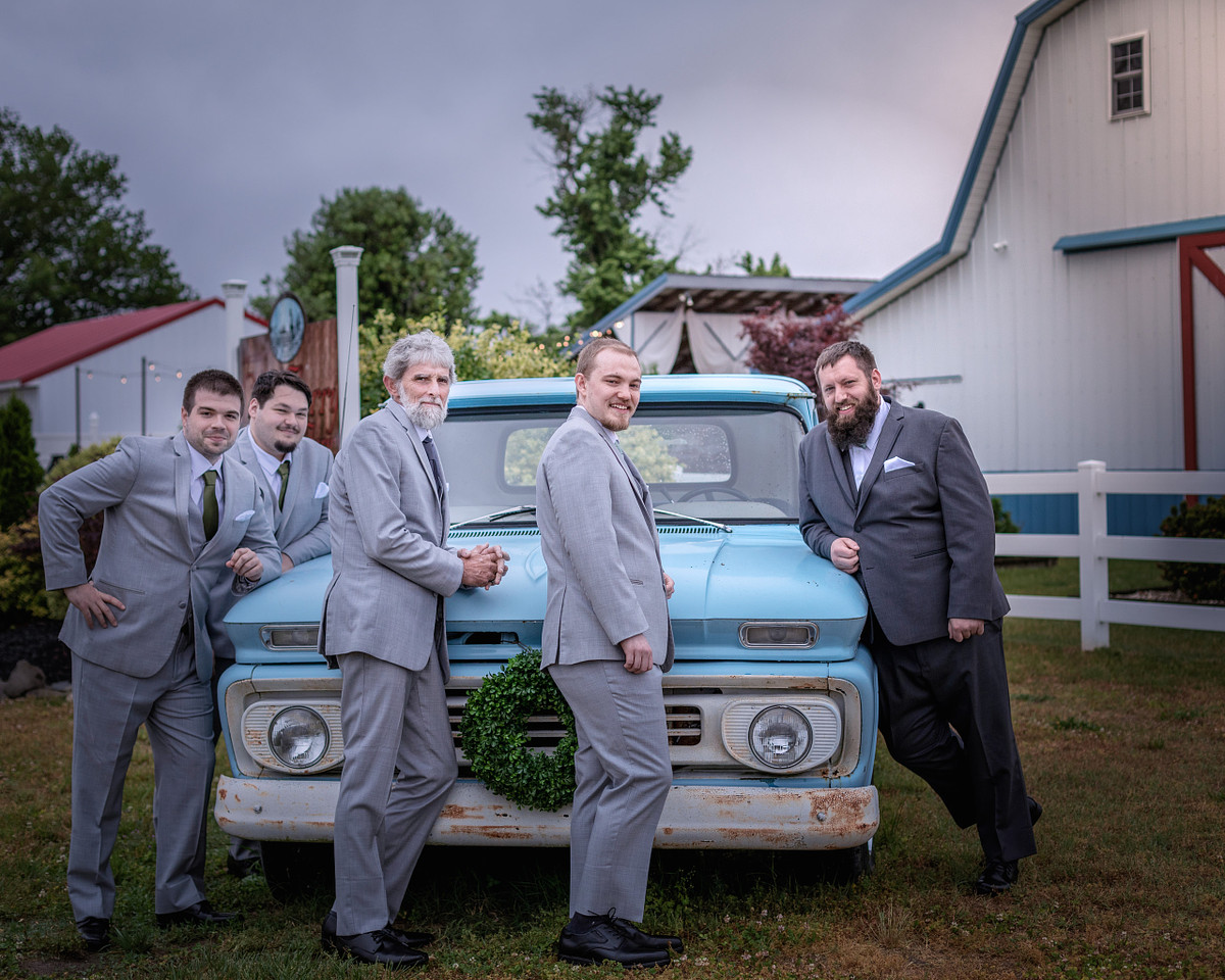 groom and groomsmen posing in front of an antique car at chickberry farm in laurel, delaware