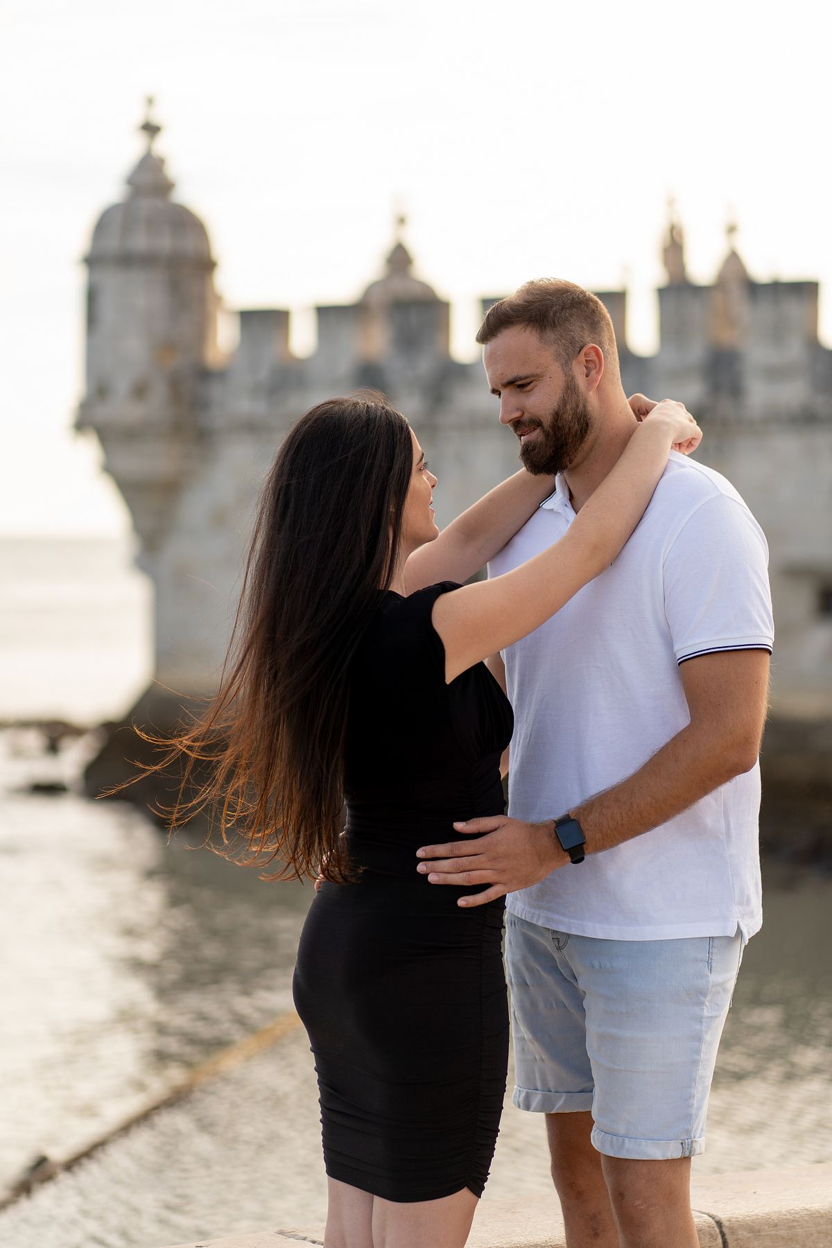 Couple embracing near a historic Lisbon landmark