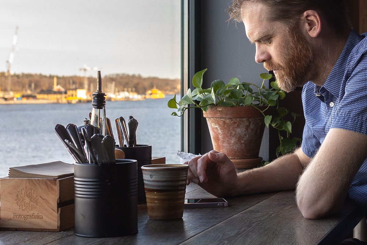 Person sitting by a caf&eacute; window in Stockholm, photographed with natural light in an editorial portrait style