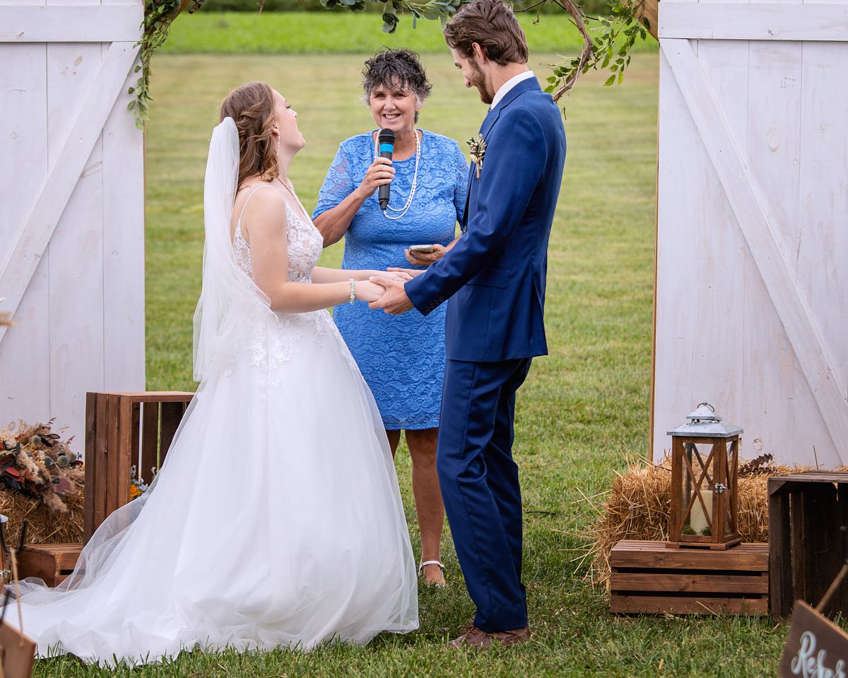 candid moment between the bride and groom laughing at the minister at a farm wedding in Harrington, DE