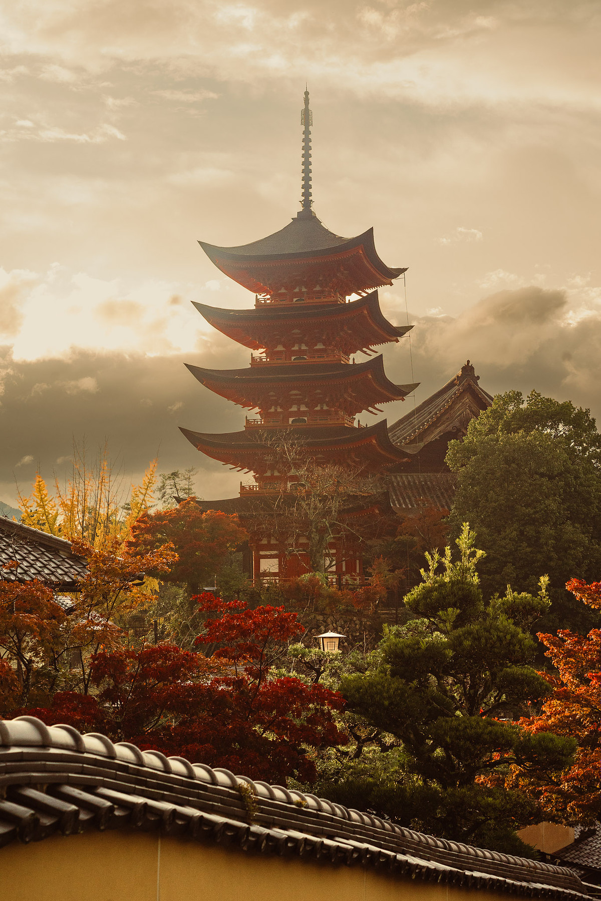 La pagode à cinq étages Gojūnotō de Miyajima au dessus des érables, avec un toit de tuiles au premier plan