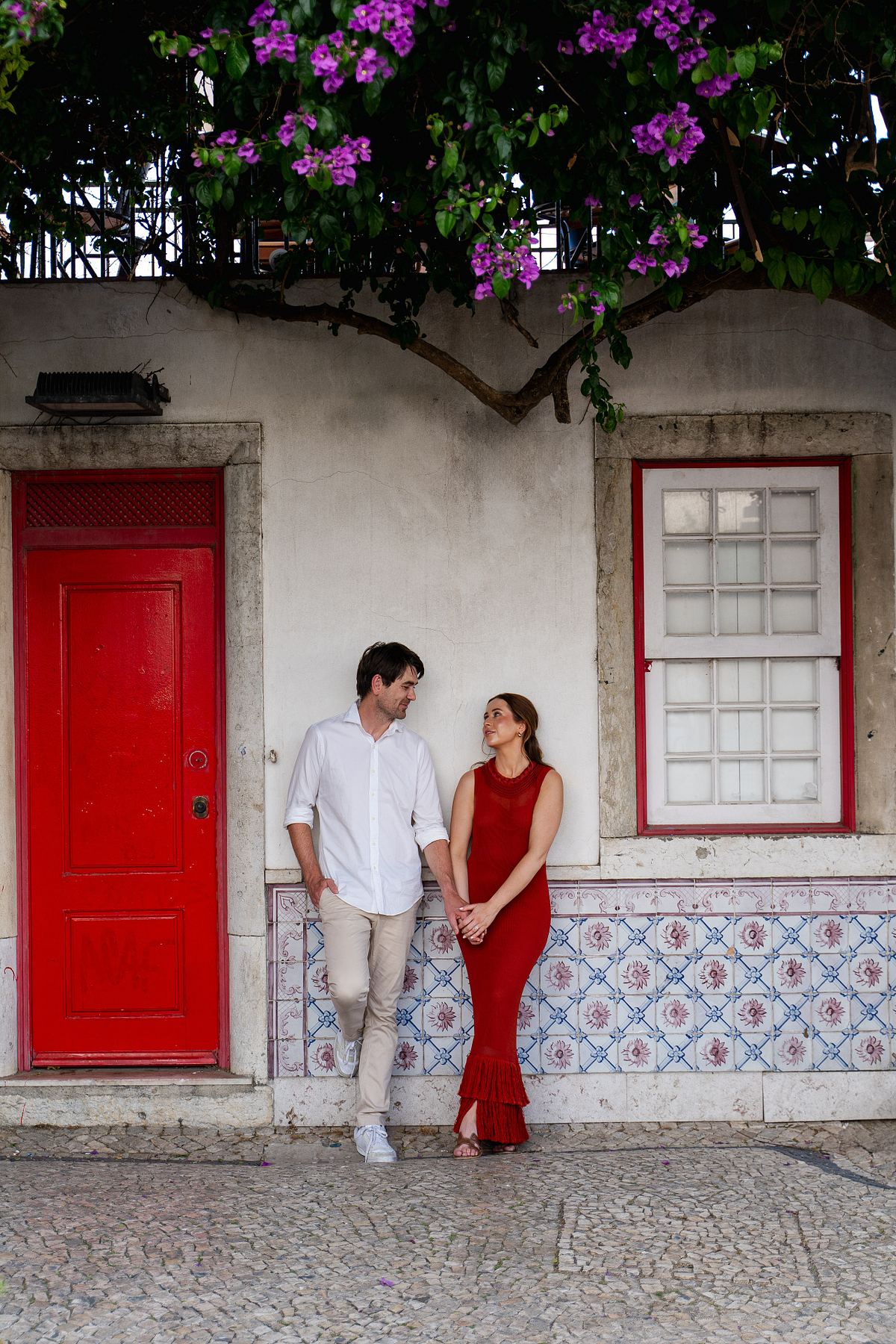 Couple posing beside a red door and traditional Lisbon tiles