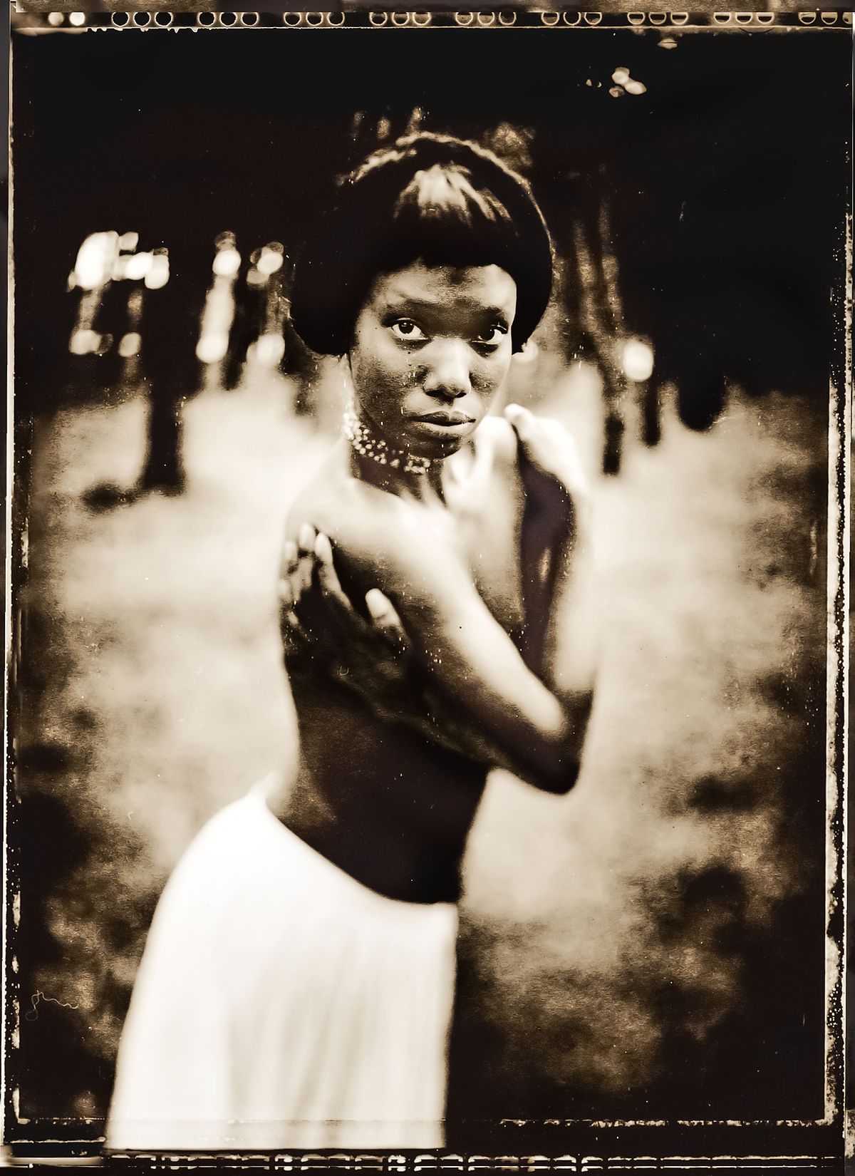 Portrait of a girl in a forrest topless, with her arms crossed in front of her.