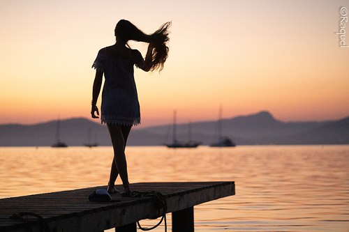 Silhouette d'une jeune fSilhouette d’une jeune femme photographe au coucher du soleil face à la Méditerranée à Hyères.