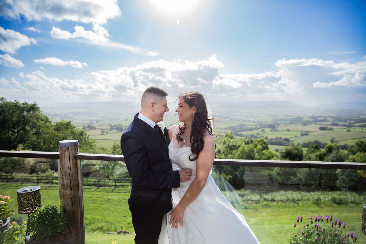 Bride and groom standing on a sunny terrace overlooking the Welsh countryside, photographed by Marta Vershynina South Wales wedding photographer