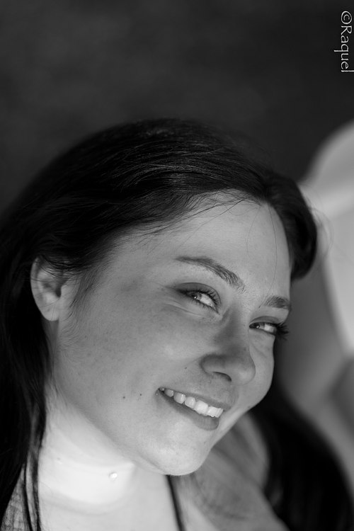 Portrait en noir et blanc d’une jeune femme souriante regardant hors champ.