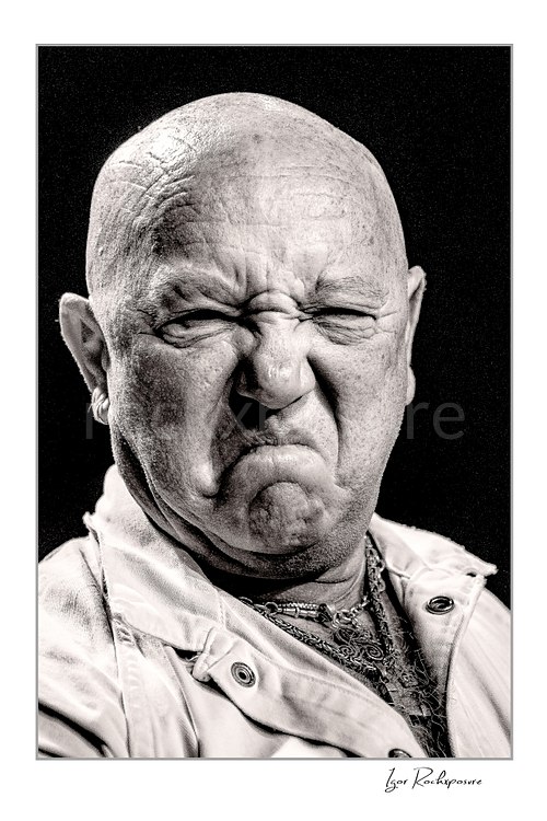 Vertical black and white image of Angry Anderson of Rose Tattoo in a tight onstage close-up with a fierce expression