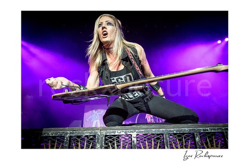 Horizontal color image of Nita Strauss performing live on stage with an electric guitar