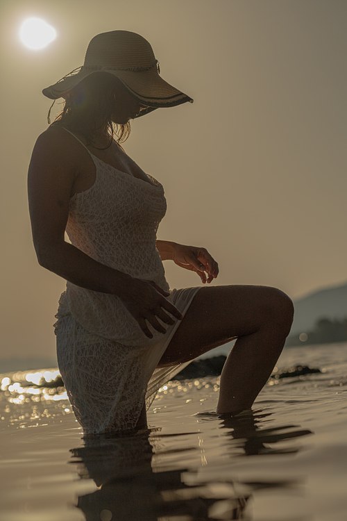 Portrait de femme en robe et chapeau marchant dans la mer à Carqueiranne