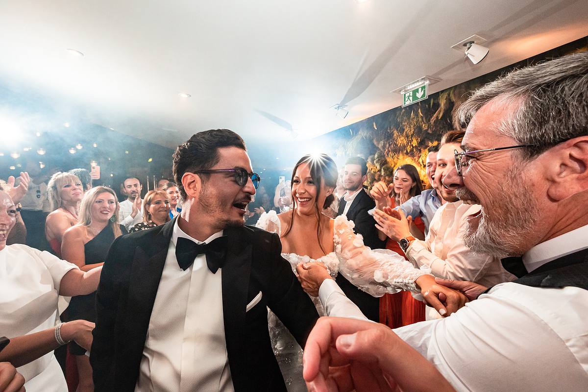 Les jeunes mari&eacute;s partagent un moment de complicit&eacute; et de joie, entour&eacute;s d'amis exub&eacute;rants, une sc&egrave;ne festive capt&eacute;e par Sebastien CLAVEL Photographe mariage Lyon au Pavillon du Casino Lyon vert