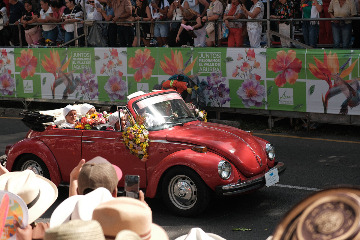 Red vintage Volkswagen Beetle covered in flowers during the classic car parade at Feria de las Flores in Medellin