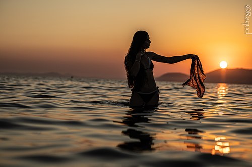 Silhouette d'une jeune femme jouant avec la lumière du soleil sur la mer à Hyères.