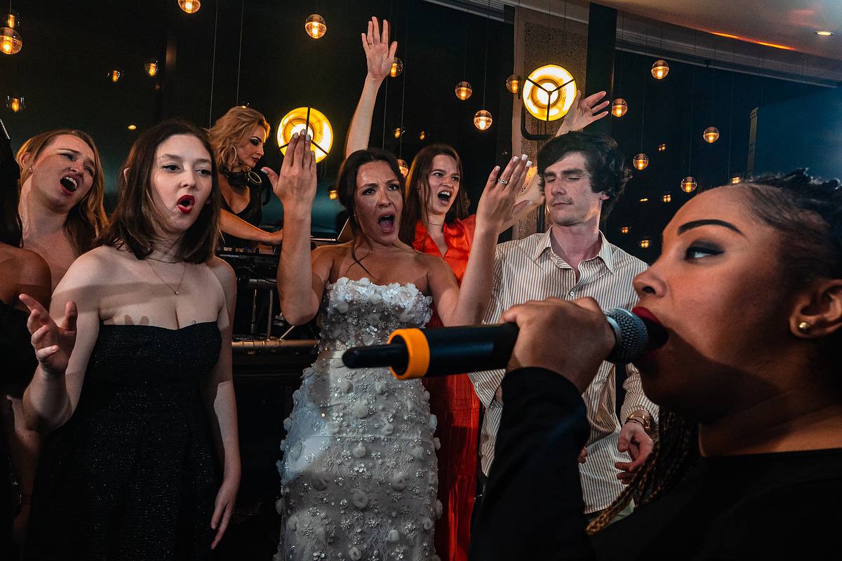 La mari&eacute;e, micro en main, chante passionn&eacute;ment, entour&eacute;e d'amis imitant les stars de la pop, dans une ambiance de concert chic au Pavillon du Casino Lyon vert, par Sebastien CLAVEL Photographe mariage Lyon