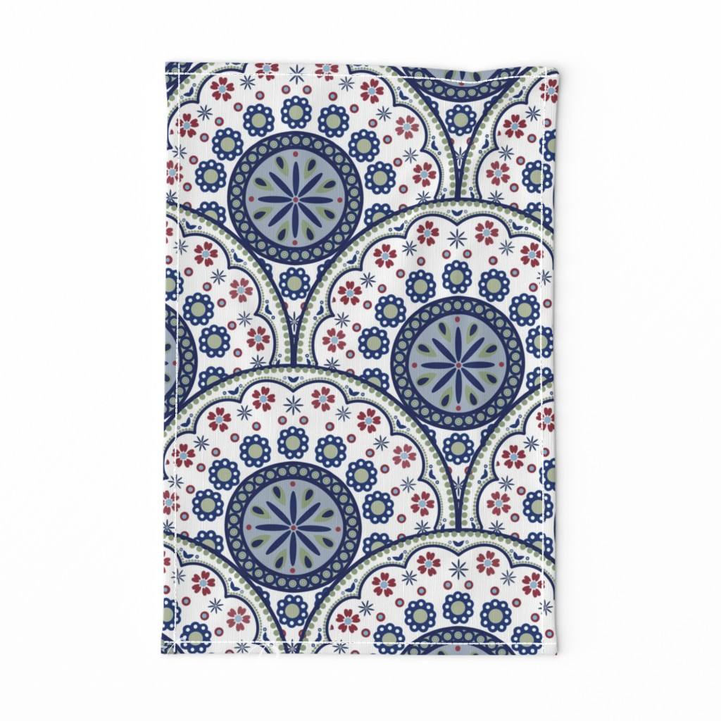 Tea towel featuring a Polish folk art-inspired medallion pattern in navy blue, sage green, red, and white with floral and geometric details.