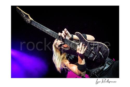 Horizontal color image of Nita Strauss performing live on stage with an electric guitar