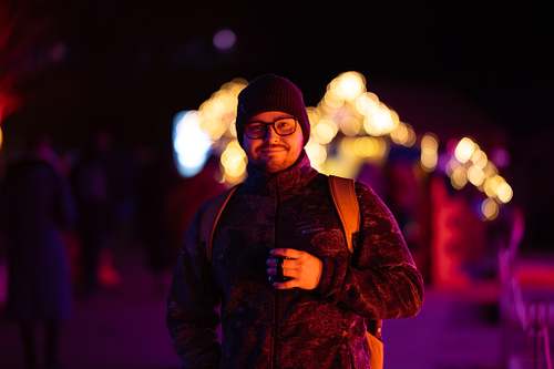 Porträt eines Mannes mit Mütze und Brille abends auf dem Weihnachtsmarkt