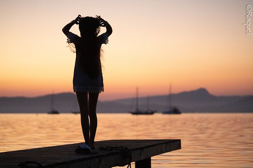 Silhouette d'une jeune femme au coucher du soleil sur le littoral de Hyères dans le Var.