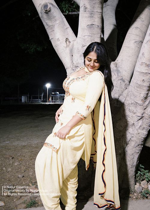 Elegant evening portrait featuring Nupur Ahuja in a yellow Punjabi suit beside a tree.