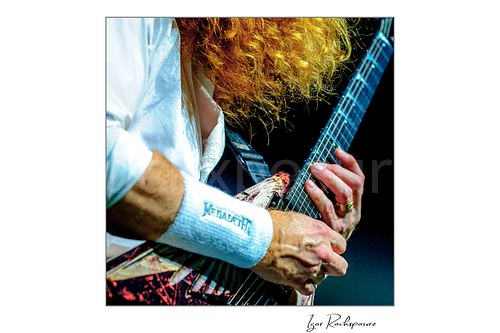 Square color image of Dave Mustaine of Megadeth in a tight close-up playing guitar, showing red hair, hands, and a Megadeth wristband