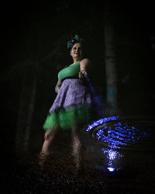 A powerful woman sprinkles magic into her reflection in the water.