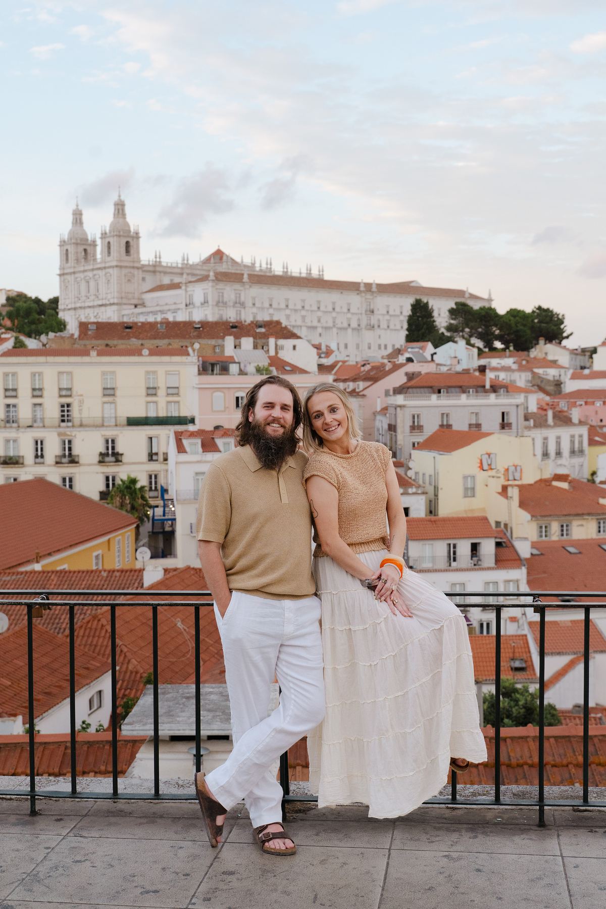 Couple standing together at a Lisbon viewpoint overlooking Alfama