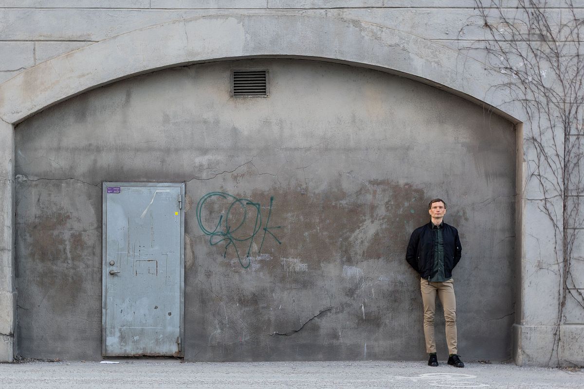 Person standing against a textured concrete wall in Stockholm, photographed in a natural editorial portrait style