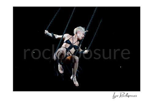 Horizontal color image of Pink suspended high above the stage on ropes during a dramatic live performance