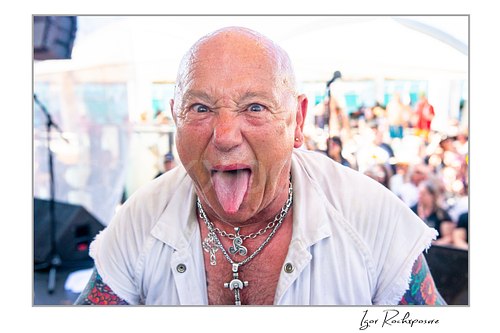Horizontal color image of Angry Anderson of Rose Tattoo in a tight onstage close-up sticking out his tongue toward the camera