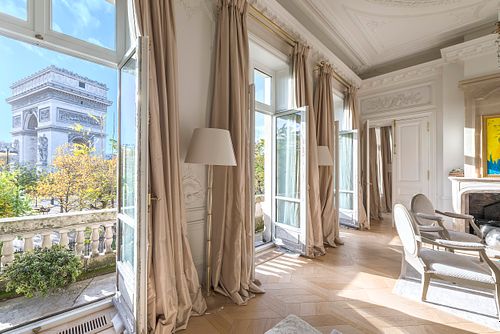 Salon haussmannien dans un immeuble de 1880 à la Place de l’Etoile, Paris, avec vue directe sur l’Arc de Triomphe depuis les grandes fenêtres. Photographie d’architecture intérieure par Nicolas Karadimos.