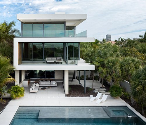 An aerial architectural photograph of a modern geometric luxury home in the Lido Shores neighborhood of Sarasota, Florida, featuring white clean lines and a rooftop terrace.
