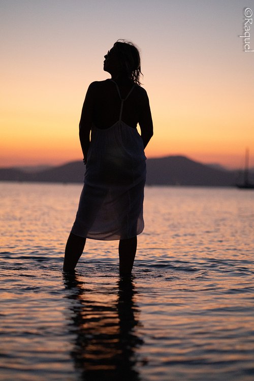 Silhouette d’une femme debout dans la mer au coucher du soleil à Hyères, séance photo lifestyle en bord de mer.
