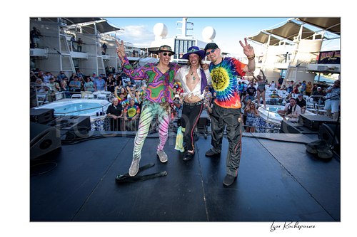Horizontal color image of Randy Hansen with band members posing on an outdoor ship deck stage before a large crowd