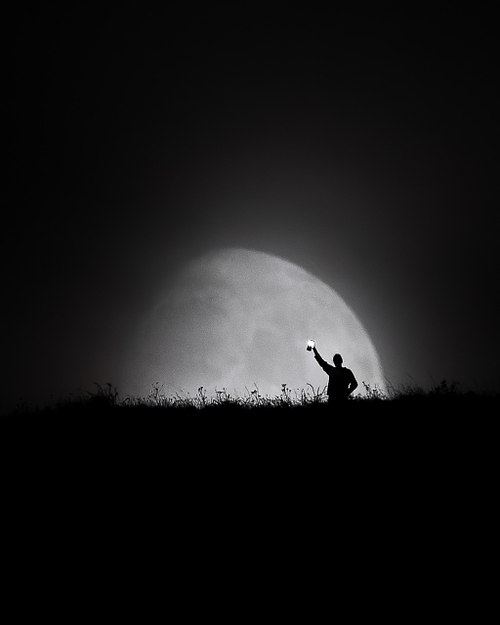 person in front of a huge moon