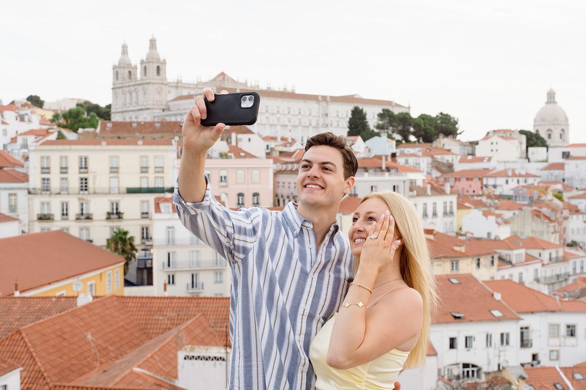 Couple taking a selfie and showing their engagement ring in Lisbon