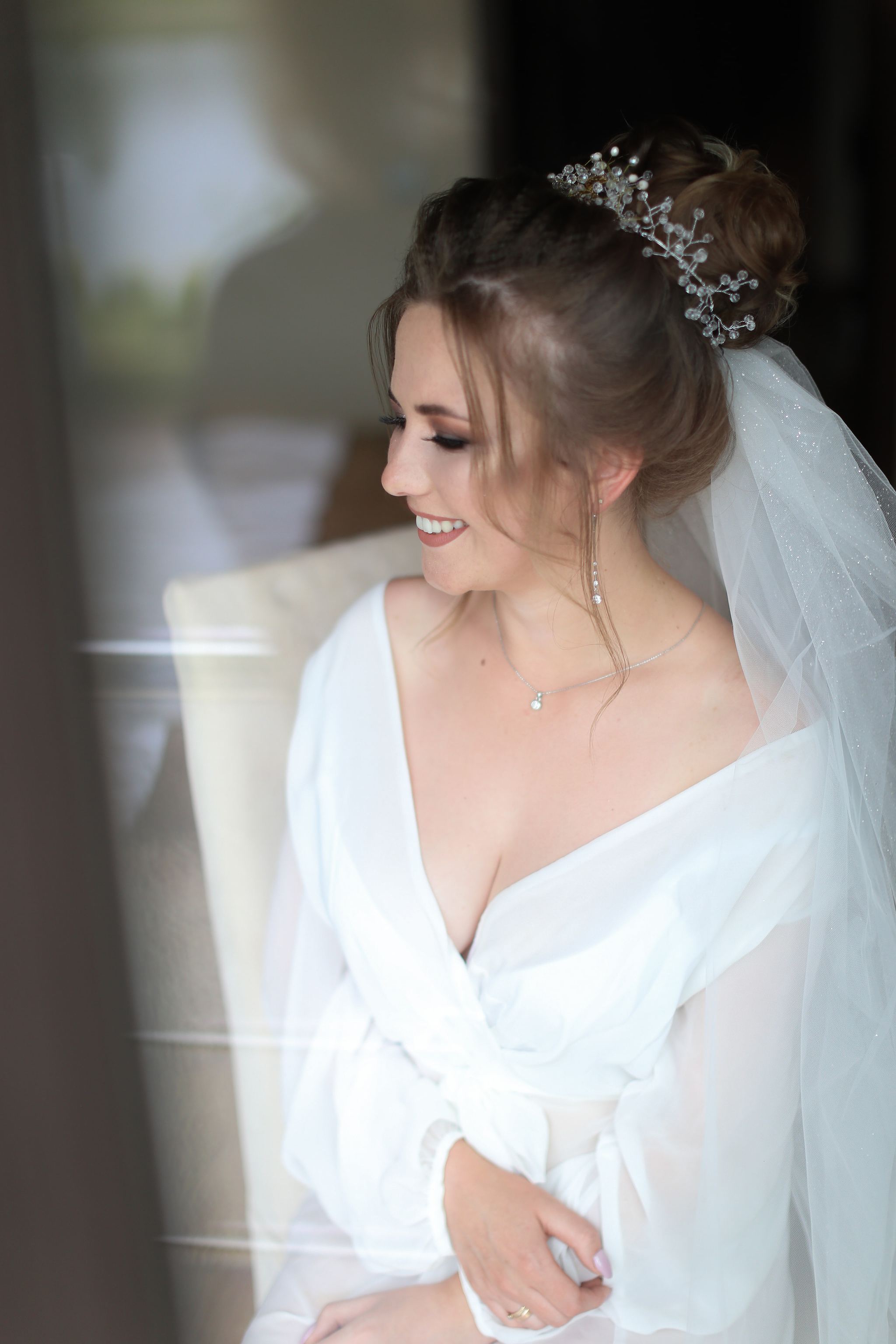 Natural bridal portrait by the window on the wedding morning in Ukraine