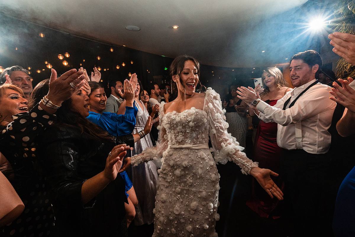 La mari&eacute;e rayonne de bonheur, traversant une haie d'honneur d'invit&eacute;s applaudissants et souriants, immortalis&eacute;e par Sebastien CLAVEL Photographe mariage Lyon dans l'atmosph&egrave;re chaleureuse du Pavillon du Casino Lyon vert