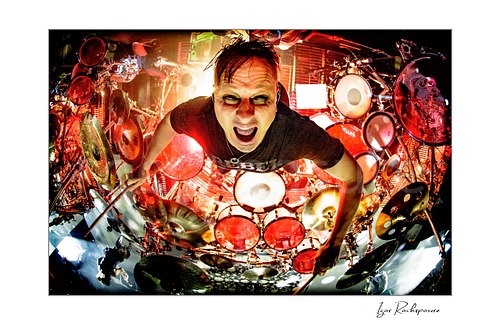 Horizontal color image of Korn drummer Ray Luzier in an aerial overhead drummer shot with drumsticks raised and an intense expression