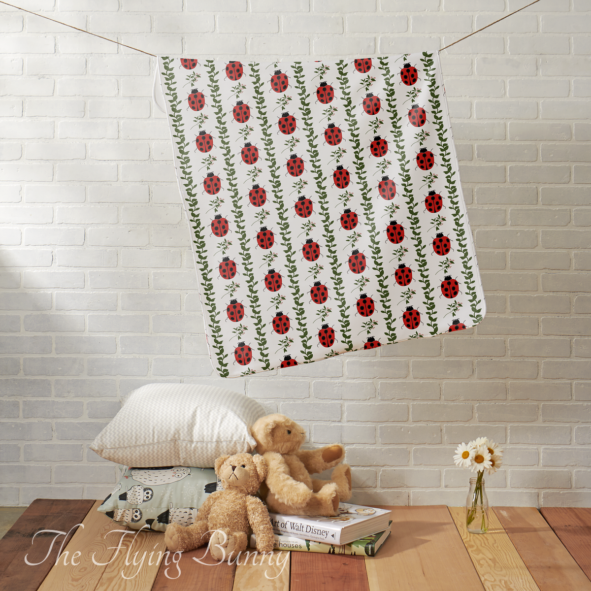 Baby blanket featuring a high-contrast pattern of bright red ladybugs and green leafy vines on a white background.
