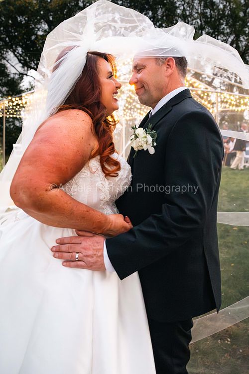 A brides veil floats above as the newlyweds embrace