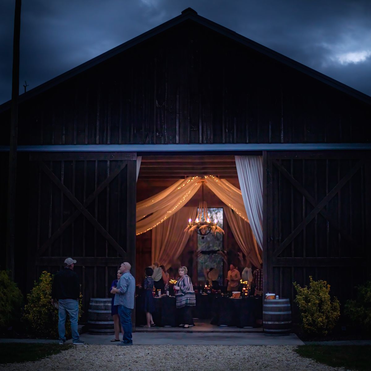 night time photo of the barn with the barn doors open and a view of the chandelier at cohee barn wedding venue, near cambridge, md