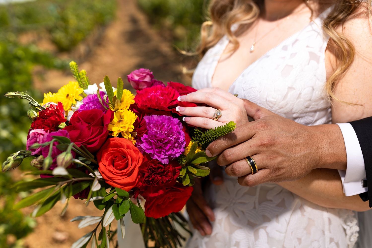 Bride and groom showing their wedding rings beside a colorful bridal bouquet in Valle de Guadalupe