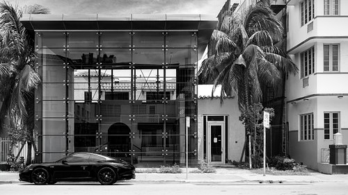 Monochromatic shot of a sleek glass structure next to a vintage hotel on Ocean Drive, Miami Beach.