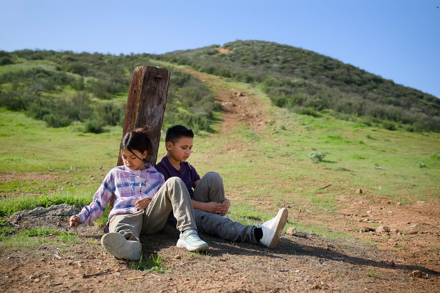 Children resting on a hillside during a family portrait session.