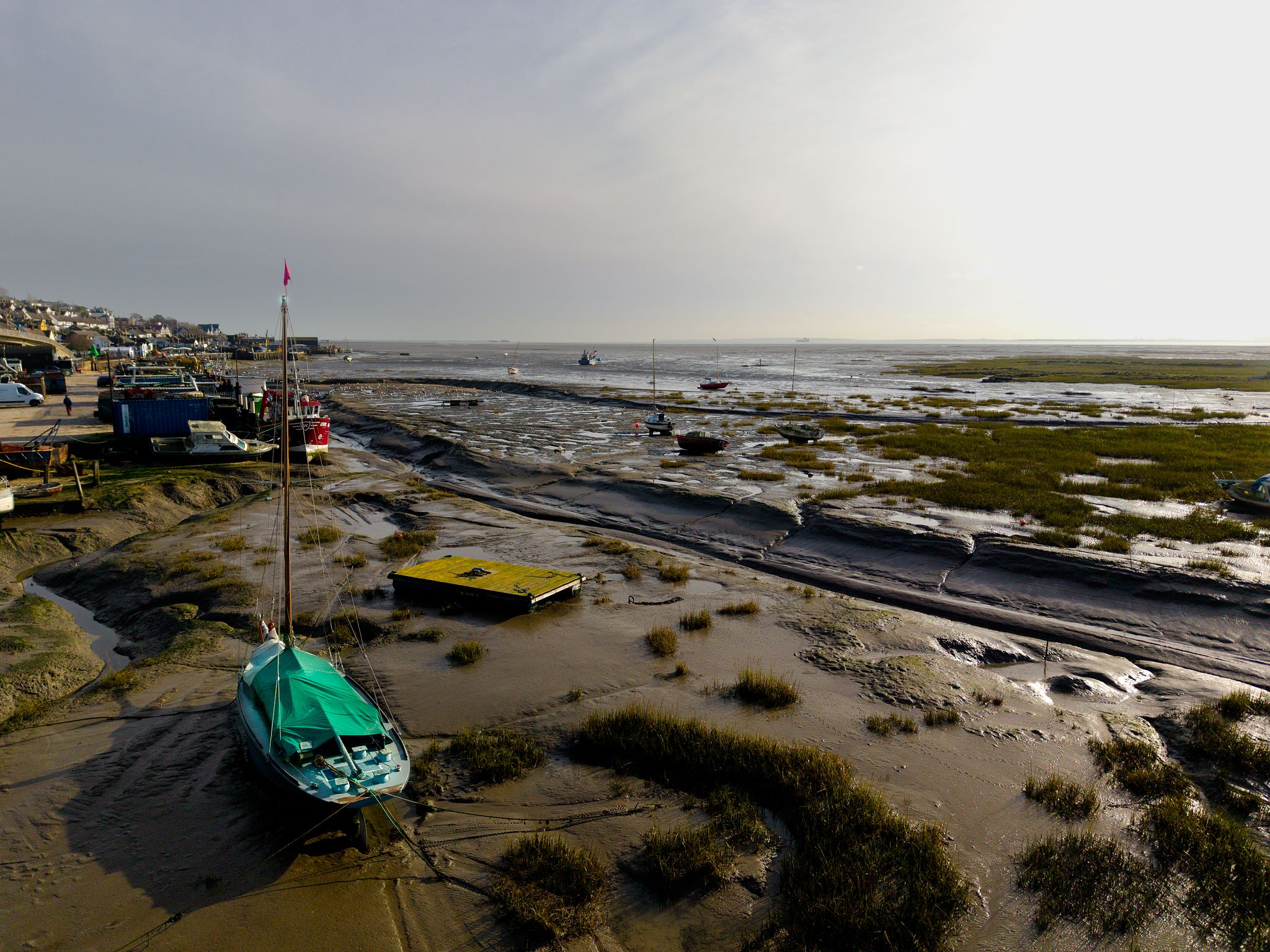 Aerial drone photograph of a lone boat resting on tidal mudflats during low tide