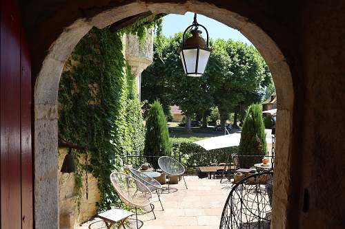 Vue sur la terrasse fleurie et la lanterne ancienne du Château de Saint-Chamarand. Un cadre paisible pour vos séjours de groupe dans le Lot.