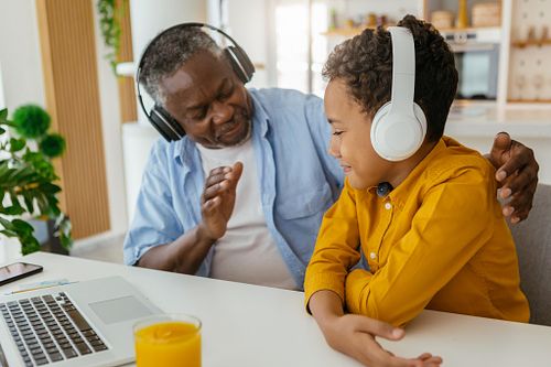 African grandfather and grandson sitting at home and listening to music together. Family having a good time together.