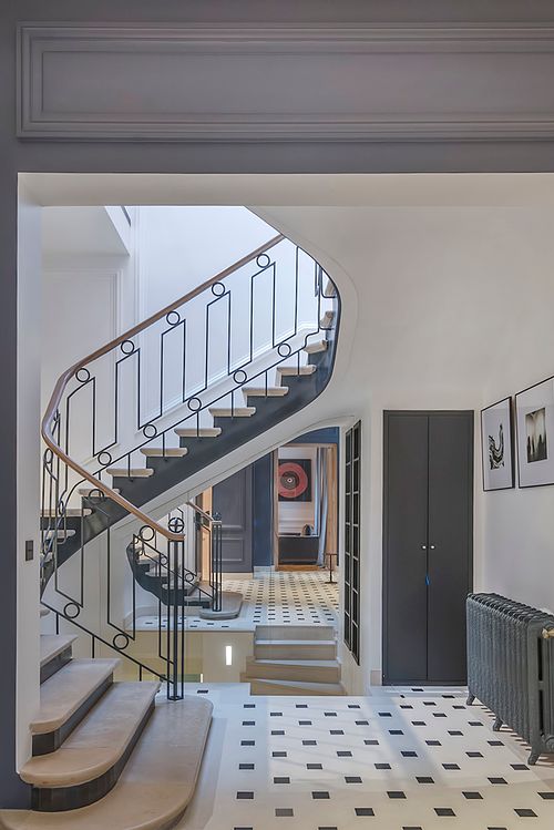 Escalier courbe avec rampe noire et blanche dans un appartement haussmannien sur les Champs-Élysées, Paris. Photographie d’architecture intérieure par Nicolas Karadimos.