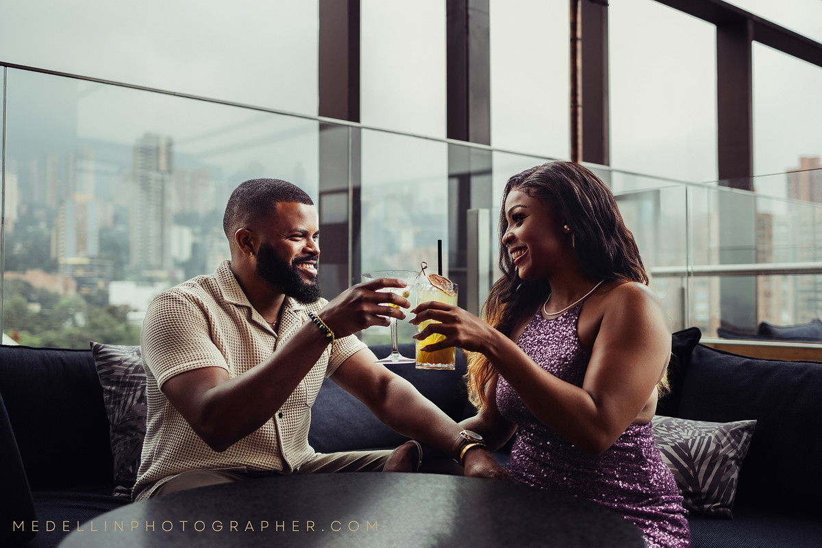 Couple toasting cocktails at a rooftop lounge overlooking the Medellin skyline