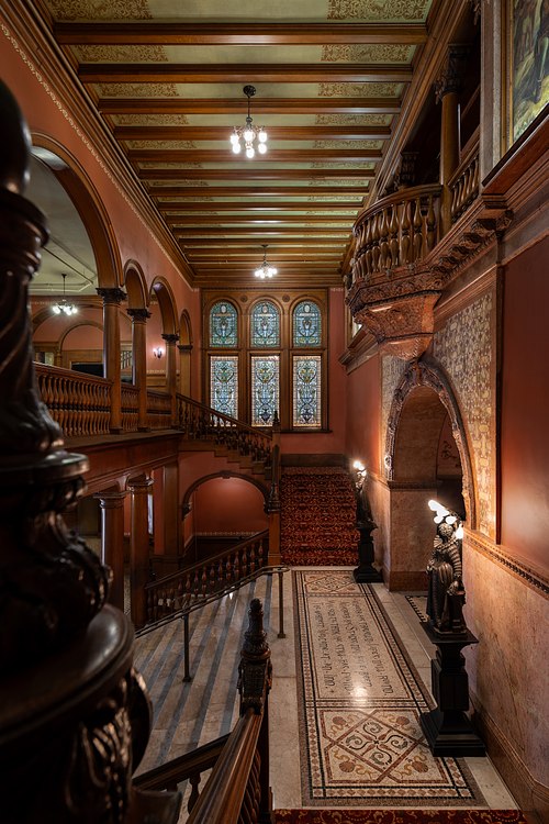Carved wooden stairwell railing, mosaic tile floor, and stained glass in the Dining Hall foyer at Ponce de Leon Hall.